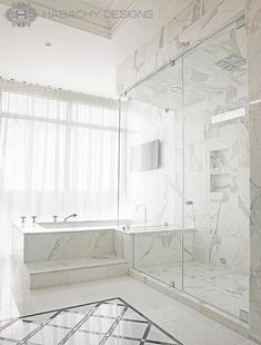 a bathroom with marble walls and flooring next to a bathtub in front of a window