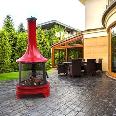 a red fire pit sitting in the middle of a patio next to a table and chairs