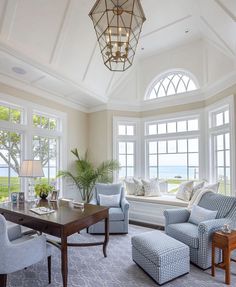 a living room filled with furniture next to a large window covered in lots of windows