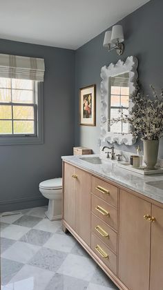 a white toilet sitting next to a sink in a bathroom under a window with curtains