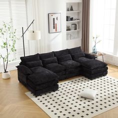 a black sectional sofa sitting on top of a wooden floor next to a white rug