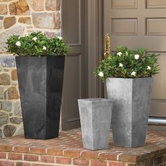 two cement planters sitting on top of a brick step next to a front door