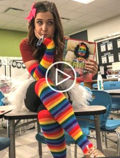 a woman sitting on top of a chair holding a book in her hand and wearing rainbow socks