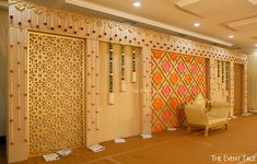 a room decorated in gold and orange with an intricate design on the wall, along with two chairs