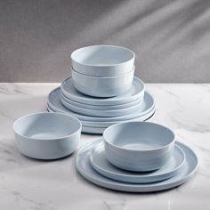 a table topped with plates and bowls on top of a white marble countertop next to a gray wall