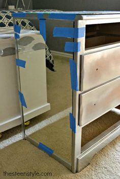 a mirrored dresser with blue tape on the top and bottom part, in front of a bed