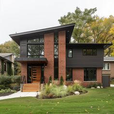 a modern house in the middle of a grassy area with trees and bushes around it