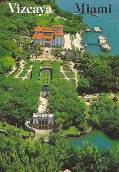 an aerial view of a large mansion surrounded by trees and water with boats in the background