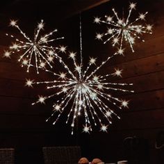 two people are sitting at a table under a large starburst chandelier