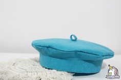 a blue hat sitting on top of a white table next to a small piece of cloth