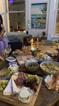 a woman sitting at a table filled with plates of food and wine glasses on it