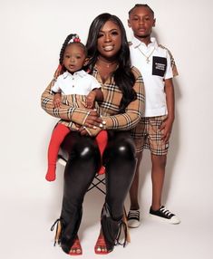 a woman sitting on top of a chair next to two young boys in matching outfits