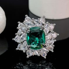 ✰Introducing our latest Paparacha Zirconia Ring featuring an emerald-cut gemstone in mesmerizing lake blue hue, encircled by white marquise and teardrop cubic zirconia. Meticulously crafted to exude charm and luxury, this stunning piece elevates your style, adding an air of elegance and sophistication to any ensemble. ✰ Crafted with precision, this eye-catching ring is made from copper and plated with 18k white gold, ensuring both durability and a luxurious shine. The adjustable design allows fo Dazzling Green Diamond-cut Rings, Dazzling Green Emerald Ring Gift, Dazzling Green Diamond Cut Ring, Formal Green Emerald Cut Crystal Ring, Formal Green Emerald-cut Crystal Ring, Green Cubic Zirconia Ring With Halo Setting, Green Emerald-cut Crystal Ring With Center Stone, Formal Green Crystal Ring With Halo Setting, Green Emerald Cut Crystal Ring With Center Stone