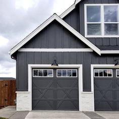 a gray house with white trim and two garage doors on the front, and one side of the house