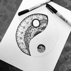 a drawing of a yin - yang symbol on paper next to a pen and marker