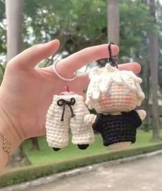 a hand holding two small crocheted items in the shape of sheep and man