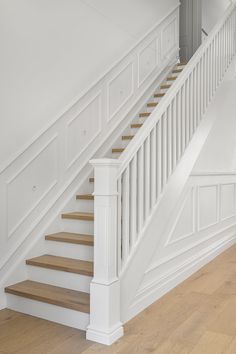 a white staircase with wooden handrails and wood flooring