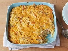 a casserole dish with cheese and vegetables in it on a blue plate next to a fork