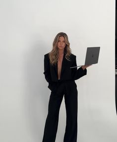 a woman in a black suit holding a laptop