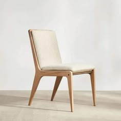 a white chair with a wooden frame and seat cushion on the back, in front of a wall