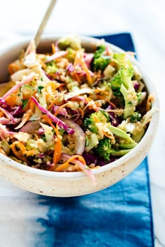 a bowl filled with broccoli, carrots and coleslaw on top of a blue napkin