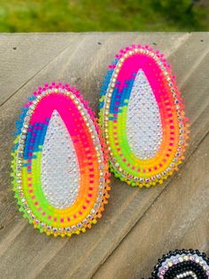 two pairs of colorful beaded earrings sitting on top of a wooden table next to each other