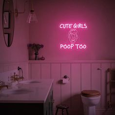 a bathroom with a pink neon sign above the toilet and sink in front of it