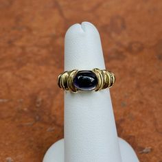 Estate/ vintage 14KT Yyllow gold Etruscan style purple, cabochon iolite ring by Via America Jewelry Company. Super cool + unique vintage style! Size 5 Can be resized for an additional fee Weight: 7.30 grams Band width: 8.5mm Tapers in back Iolite measures: 9mm x 7mm Oval, cabochon, Iolite Genuine iolite stone Stamped 14K, guaranteed 14K, and hallmarked Great estate condition Iolite Ring, Iolite Stone, Jewelry Companies, Oval Cabochon, Super Cool, Unique Vintage, Vintage Style, Vintage Fashion, Yellow Gold