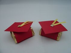 two red graduation caps with gold ribbons on them, one is folded and the other is folded