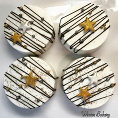 four cupcakes decorated with white and gold icing, stars and chocolate drizzle