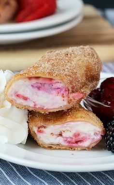 two pastries on a plate with berries and whipped cream