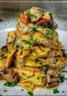 a white plate topped with pasta covered in mushrooms