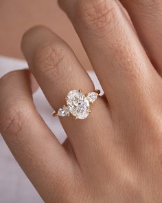 a woman's hand with a diamond ring on top of her finger and an engagement band