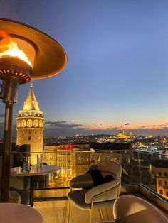 a table and chairs on top of a roof with a view of the city at night