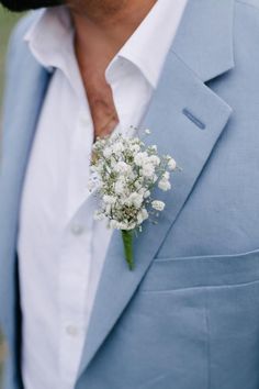 a man wearing a blue suit and white shirt with a boutonniere on his lapel