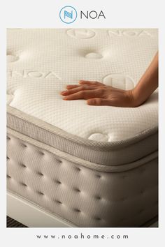 a person's hand resting on the top of a bed with noa mattress