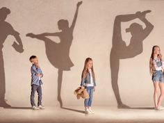 three young children standing in front of a wall with their shadow cast on the wall