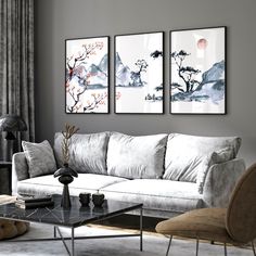 a living room with three paintings on the wall and two chairs in front of it