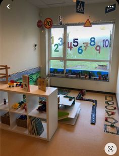 a child's playroom with toys on the floor and windows in the background