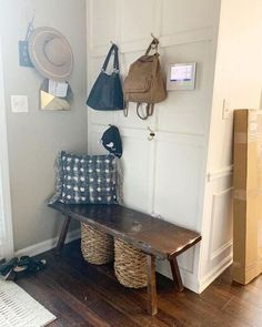 a wooden bench sitting next to a wall with baskets and bags hanging on it's side