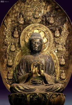 a buddha statue sitting in front of a gold plate with ornate designs on the side