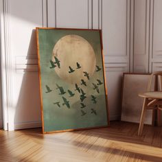 there is a painting on the floor with birds flying in front of it and a chair next to it