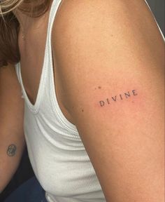 a woman's arm with the word divine tattooed on her left shoulder, in black ink