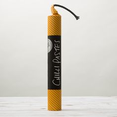 a yellow tube with black writing on it sitting on top of a wooden table next to a white wall