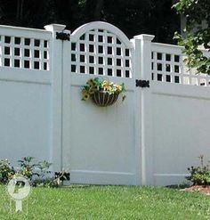 a white fence with flowers hanging on the top and bottom part, in front of it