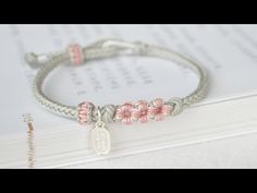 a bracelet with pink flowers on it sitting next to an open book