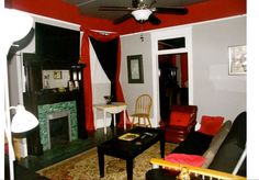 a living room with red walls and black furniture in front of a fireplace mantel