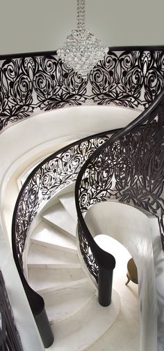 a black and white photo of a spiral staircase with chandelier hanging from the ceiling