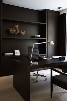 an office with black walls and wooden flooring, along with a desk that has a computer on it