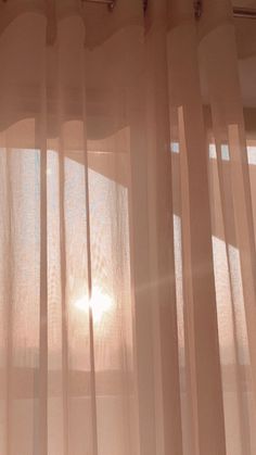 the sun is shining through sheer curtains